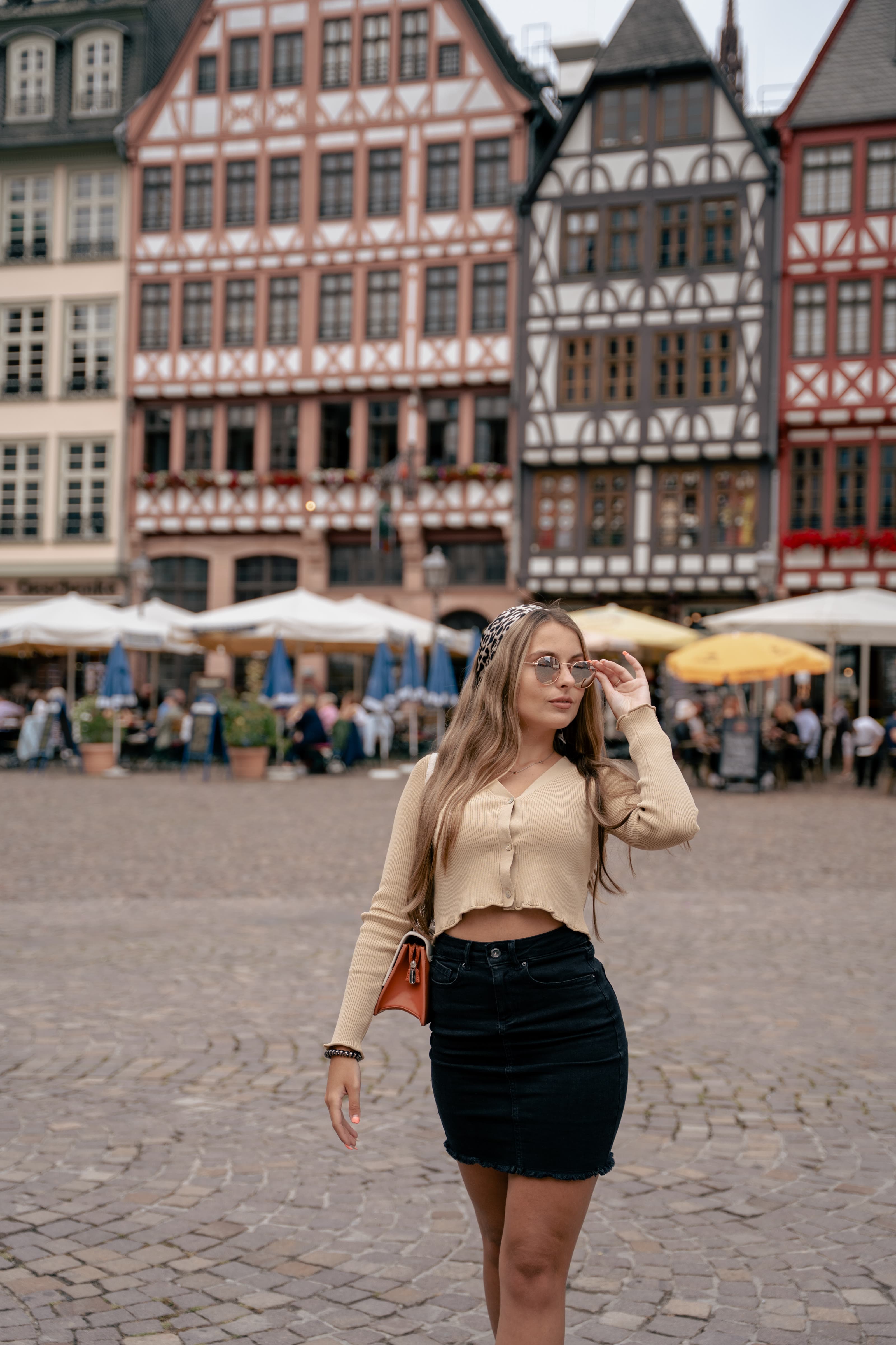 Junge Frau geht über den Römerberg, hinter ihr die Fachwerkhäuser der Ostzeile